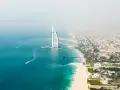 Widok z lotu ptaka na Dubaj: luksusowy hotel w kształcie żagla, piaszczysta plaża i turkusowe morze.