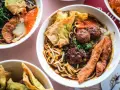 Miseczki z aromatycznymi potrawami chińskimi: makaron, mięso, kluski ryżowe, smażone pierożki i chrupiące kawałki kurczaka.