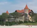 Elegancki hotel z wieżą i czerwonym dachem, otoczony drzewami, idealny na łeba atrakcje dla dorosłych.