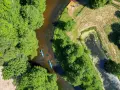 Spływ kajakowy rzeką to jedna z pięknych kociewie atrakcji. Dwie kajaki płyną wśród zielonych drzew.