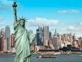 Statua Wolności wita na wycieczce do USA. W tle panorama Nowego Jorku z drapaczami chmur.