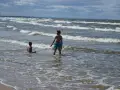 Dwaj chłopcy bawią się na kąpielisku na mierzei wiślanej. Fale delikatnie obmywają ich nogi.