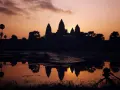 Zachód słońca nad Angkor Wat, idealne tło dla niezapomnianych kambodżańskich wakacji. Widok odbija się w wodzie, a na pierwszym planie statyw z aparatem.