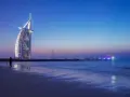 Zachód słońca nad Zatoką Perską. Widok na hotel Burj Al Arab i oświetloną łódź. Ceny w Dubaju mogą być wysokie, ale widoki są bezcenne.