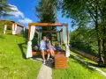 Idealne miejsce, gdzie na weekend we dwoje. Para odpoczywa na łóżku pod baldachimem w otoczeniu zieleni.