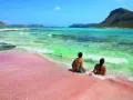 Para relaksuje się na różowej plaży Elafonisi na Krecie, z turkusową wodą i skalistymi wyspami w tle.