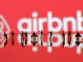 Małe figurki ludzi na tle logo Airbnb. Zastanawiasz się airbnb co to? To platforma do rezerwacji noclegów.