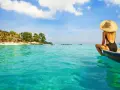 Kobieta w kapeluszu siedzi na łodzi, podziwiając turkusowe morze i tropikalne plaże na Bali.
