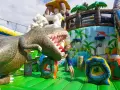 Chłopiec skacze na dmuchanym dinozaurze. Wspaniała atrakcja dla dzieci, jedno z wielu **ciekawe miejsca do 100 km od Katowic**.