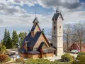Drewniany kościółek i kamienna wieża z zegarem, malowniczo położone gdzie w Karkonosze.