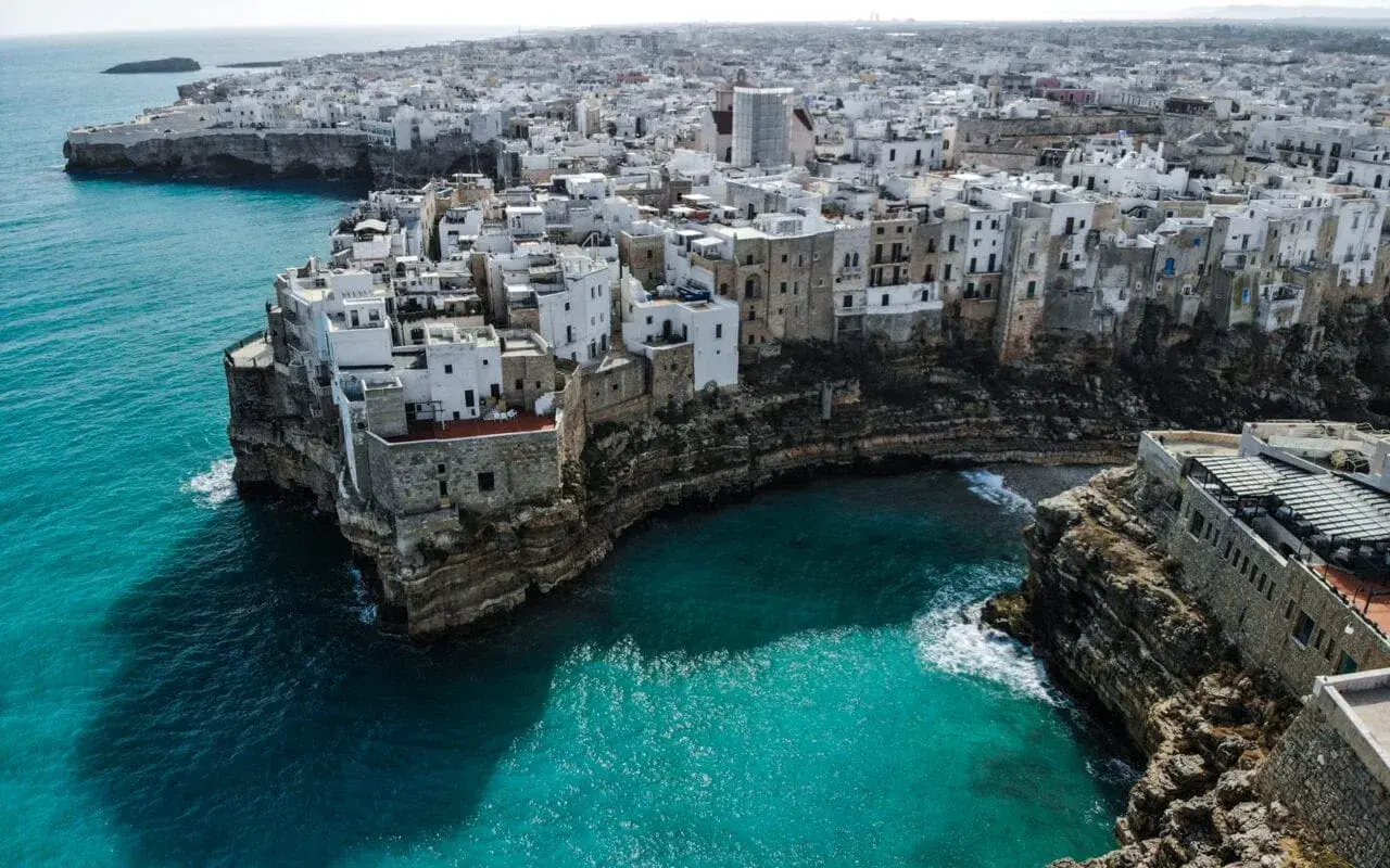 Malownicze białe domy na klifie nad turkusowym morzem. Polignano a Mare, Apulia – idealne miejsce, by wznieść toast za piękno Włoch. brindisi co zobaczyć.