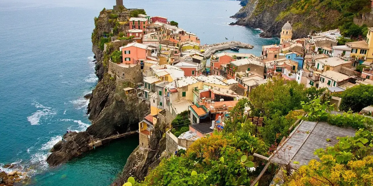 Kolorowe domy Cinque Terre na klifie, idealne na wakacyjne loty do Włoch.