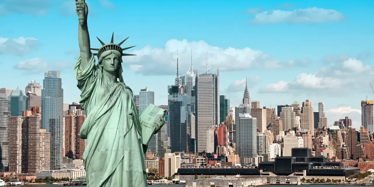 Statua Wolności wita na wycieczce do USA. W tle panorama Nowego Jorku z drapaczami chmur.