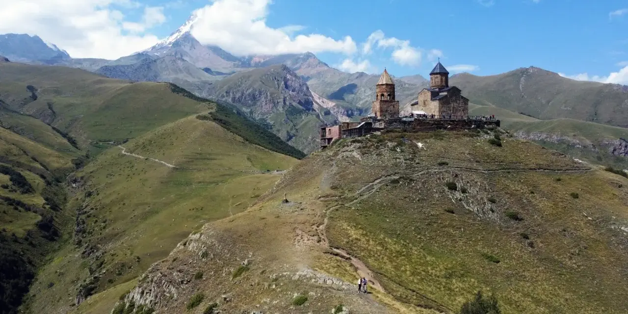 Gruzja wakacje: Kościół Gergeti na tle gór Kaukazu. Widok na malownicze doliny i szczyt Kazbek.