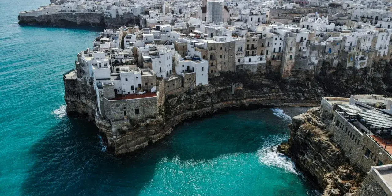 Malownicze białe domy na klifie nad turkusowym morzem. Polignano a Mare, Apulia – idealne miejsce, by wznieść toast za piękno Włoch. brindisi co zobaczyć.