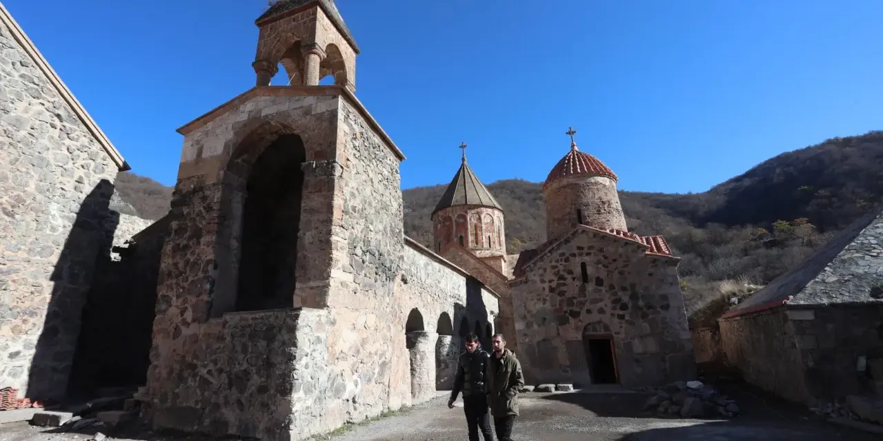 Kamienny klasztor w Armenii, świadectwo bogatej historii i religii. Dwóch mężczyzn spaceruje po dziedzińcu.