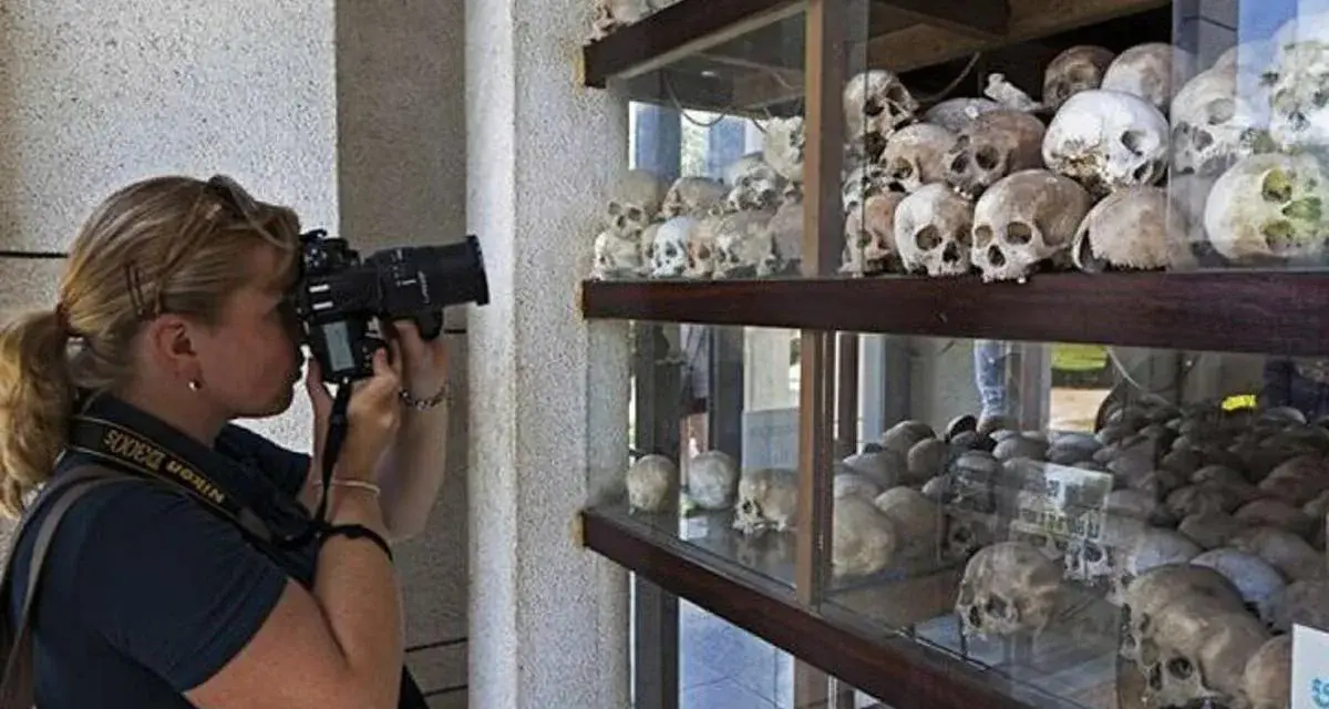 Kobieta fotografuje ludzkie czaszki na wystawie upamiętniającej pola śmierci w Kambodży.
