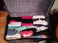 Walizka pełna ubrań, idealna odpowiedź na pytanie: co zabrać na erasmusa. Kolorowe koszulki, spodnie i bluzy czekają na podróż.