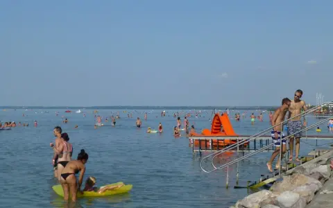 Tłum ludzi cieszy się kąpielą w Balatonie. Idealna temperatura wody zachęca do zabawy na dmuchanych zabawkach i zjeżdżalniach.