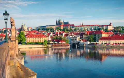 Widok na Pragę z rzeką Wełtawą i Mostem Karola, z zamkiem na wzgórzu.