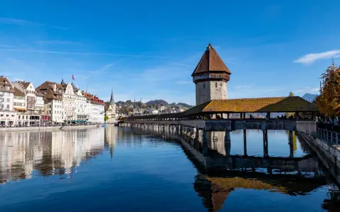 Kaplica mostowa i wieża wodna w Lucerna, miasto w Szwajcarii, odbijają się w spokojnej wodzie rzeki Reuss.