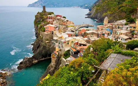 Kolorowe domy Cinque Terre na klifie, idealne na wakacyjne loty do Włoch.