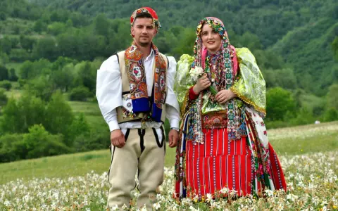Para w tradycyjnych strojach na tle zielonych wzgórz. Ciekawe albania ciekawostki o kulturze i tradycji.