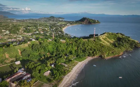 Malownicze miasto na Madagaskarze z zielonymi wzgórzami, plażą i zatoką pełną łodzi. W oddali góry.