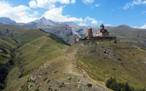 Gruzja wakacje: Kościół Gergeti na tle gór Kaukazu. Widok na malownicze doliny i szczyt Kazbek.