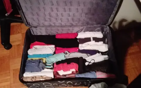 Walizka pełna ubrań, idealna odpowiedź na pytanie: co zabrać na erasmusa. Kolorowe koszulki, spodnie i bluzy czekają na podróż.