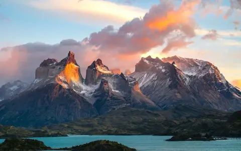 Wspaniała wycieczka do Chile! Słońce oświetla skaliste szczyty Torres del Paine, odbijając się w turkusowym jeziorze.