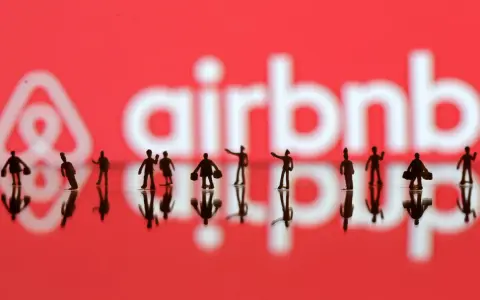 Małe figurki ludzi na tle logo Airbnb. Zastanawiasz się airbnb co to? To platforma do rezerwacji noclegów.