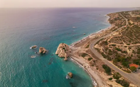 Idealny pomysł na weekend: Cypr i jego skaliste wybrzeże z turkusową wodą. Droga wije się wzdłuż plaży, zapraszając do odkrywania.
