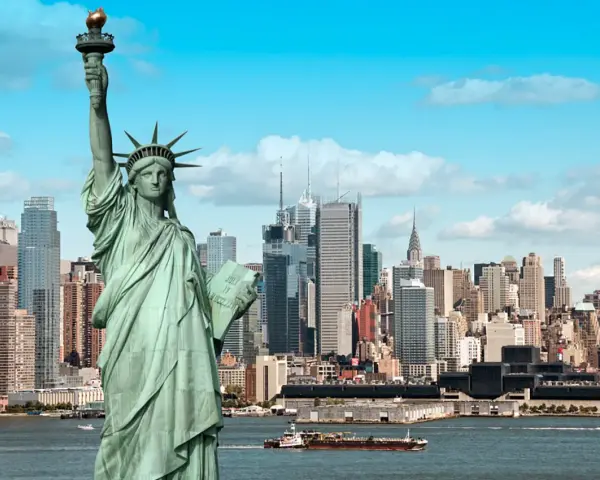 Statua Wolności wita na wycieczce do USA. W tle panorama Nowego Jorku z drapaczami chmur.