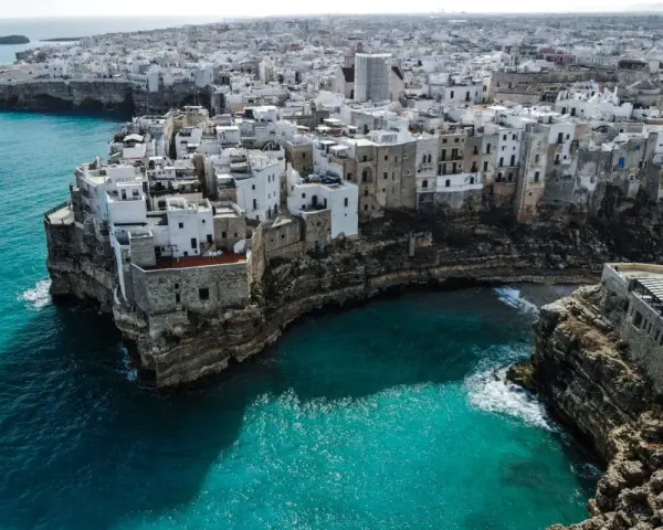 Malownicze białe domy na klifie nad turkusowym morzem. Polignano a Mare, Apulia – idealne miejsce, by wznieść toast za piękno Włoch. brindisi co zobaczyć.