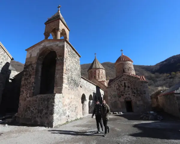 Kamienny klasztor w Armenii, świadectwo bogatej historii i religii. Dwóch mężczyzn spaceruje po dziedzińcu.