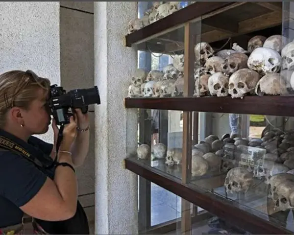 Kobieta fotografuje ludzkie czaszki na wystawie upamiętniającej pola śmierci w Kambodży.