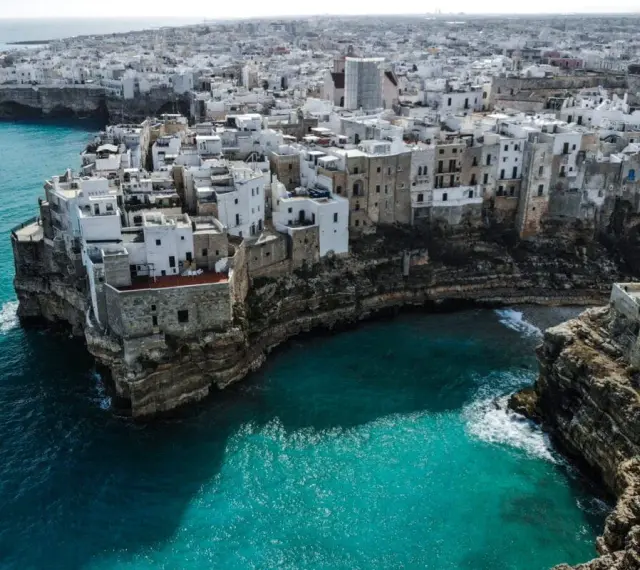 Malownicze białe domy na klifie nad turkusowym morzem. Polignano a Mare, Apulia – idealne miejsce, by wznieść toast za piękno Włoch. brindisi co zobaczyć.
