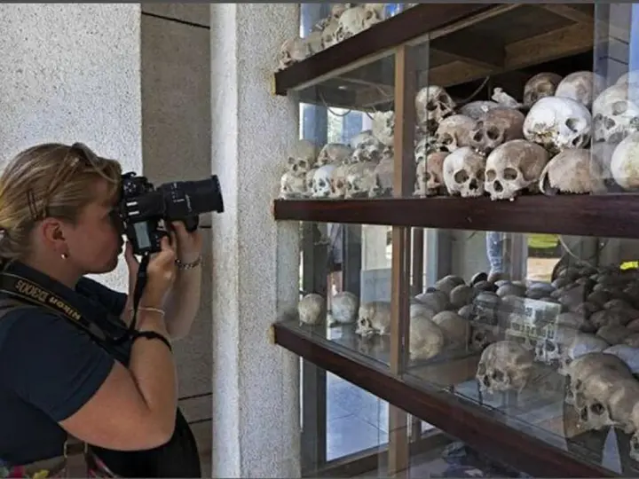 Kobieta fotografuje ludzkie czaszki na wystawie upamiętniającej pola śmierci w Kambodży.