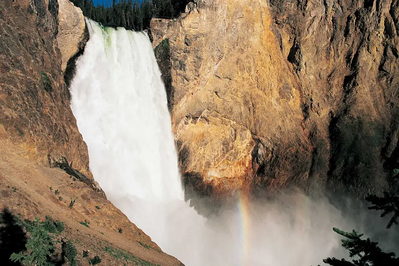 Wodospad Yellowstone, gdzie jest? Potężny strumień wody spada po skalnych ścianach, tworząc tęczę w mgiełce.