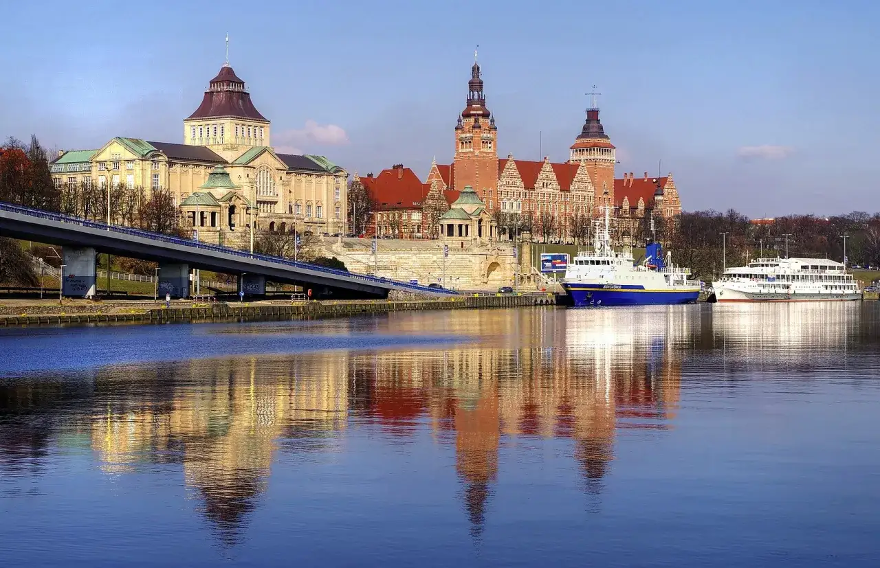 Szczecin atrakcje na weekend: zabytkowe budynki, most i statki odbijające się w Odrze.