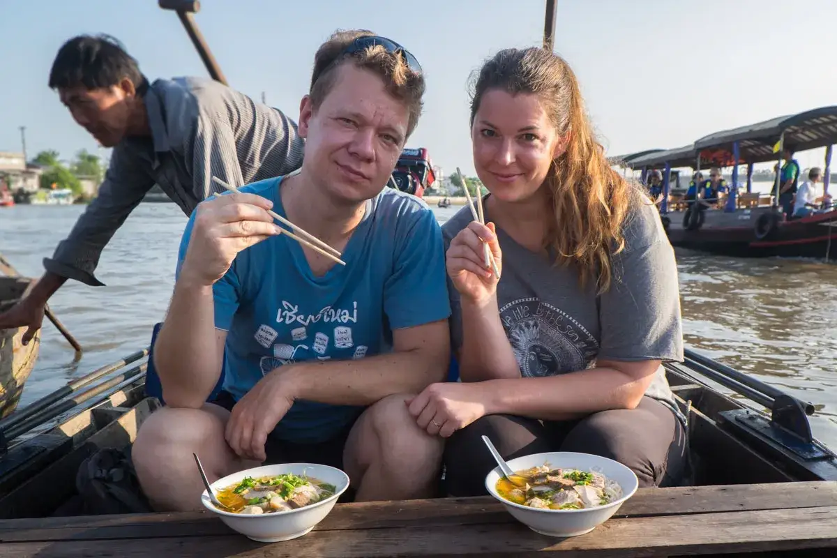 Para w łodzi na Mekongu podczas wietnamskich wakacji je lokalny makaron.