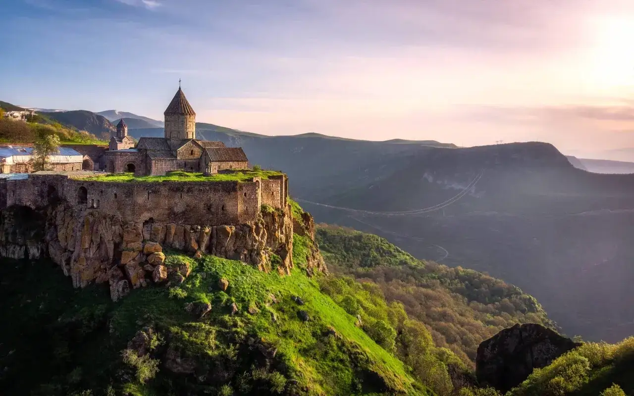 Starożytny klasztor na skale, symbol religii Armenii, otoczony zielonymi wzgórzami i mglistymi dolinami.