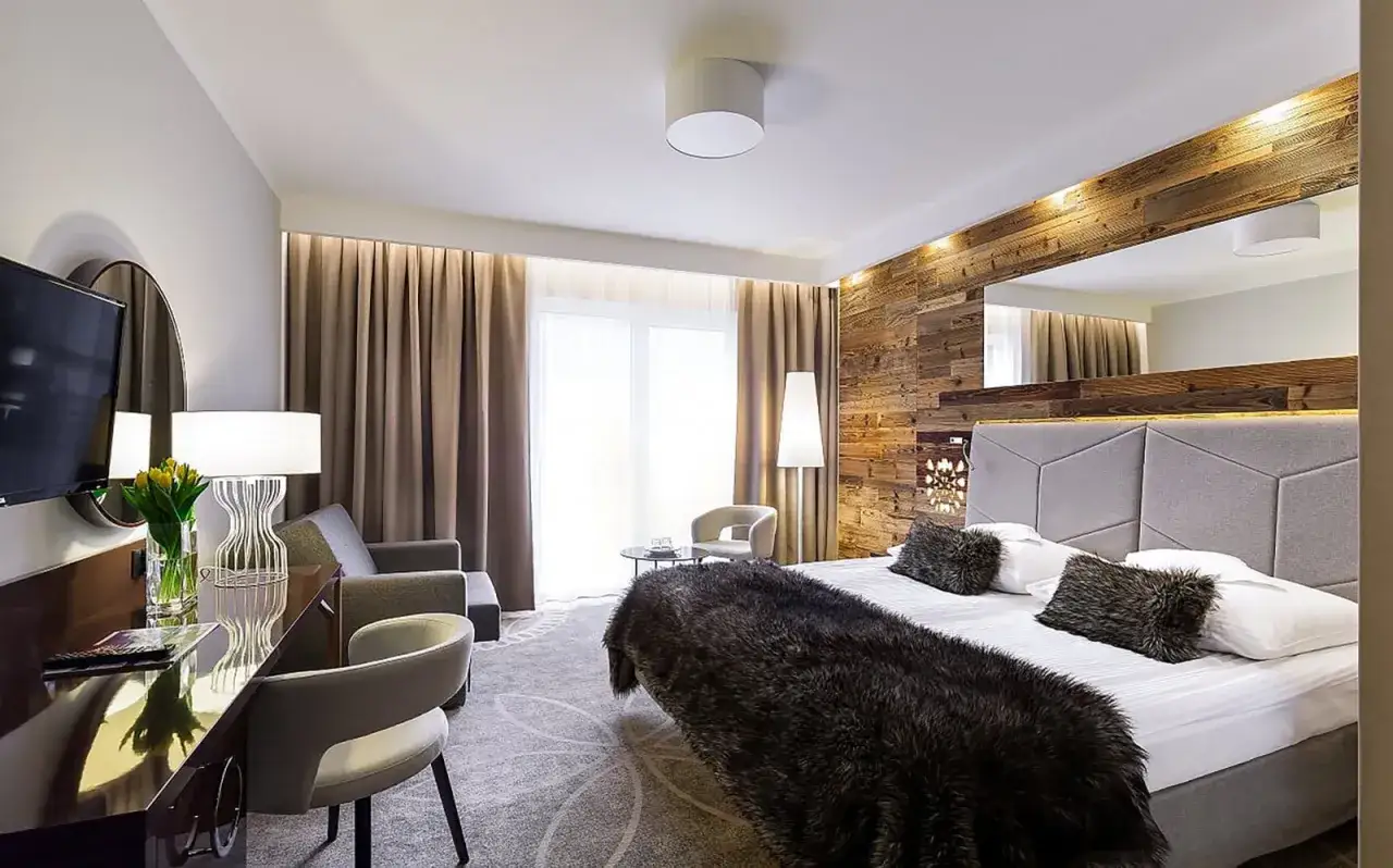 Przytulny pokój hotelowy w Karpaczu, idealny na karpacz weekend we dwoje. Drewniana ściana, wygodne łóżko i stylowe meble.